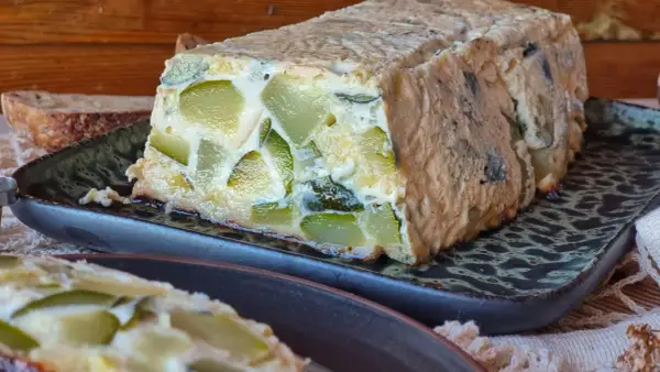 Pastel de calabacín casero, con trozos verdes visibles en una masa dorada, servido en plato oscuro.