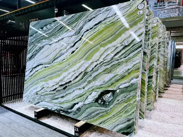 Lastre di marmo verde di prato con venature bianche e nere, esposte in un magazzino.