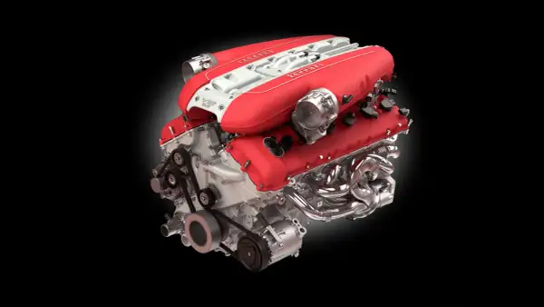 Motor V12 Ferrari rojo y blanco, ejemplo de los mejores motores gasolina, con colectores cromados y correas visibles.
