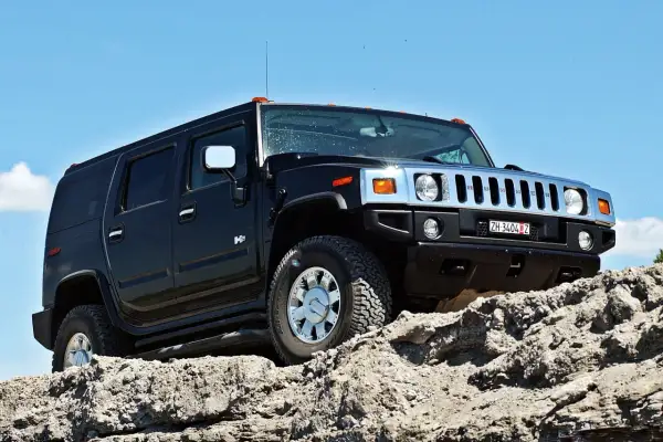 Czarny Hummer H2 pokonuje skalisty teren pod błękitnym niebem.