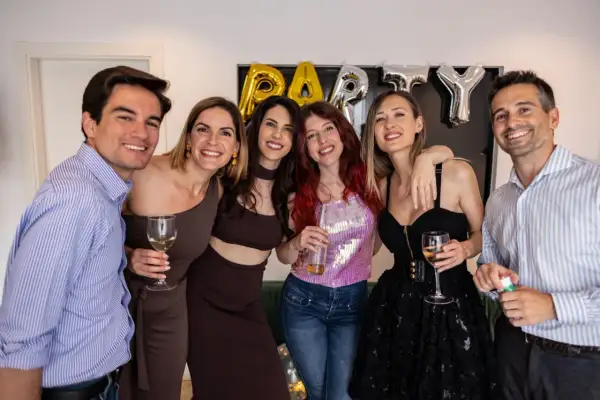 Impreza w stylu PRL! Jak się ubrać? Grupa przyjaciół świętuje, jeden mężczyzna w niebieskiej koszuli, kobiety w modnych kreacjach.