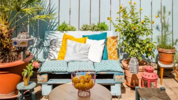 Un rincón perfecto para tus ideas chill out: un sofá de palets con cojines coloridos, plantas y faroles.