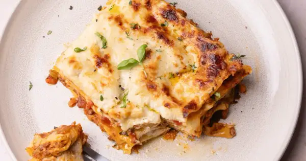 Une part de lasagne généreuse, dorée et gratinée, garnie de basilic frais. Une recette lasagne originale qui met l'eau à la bouche.