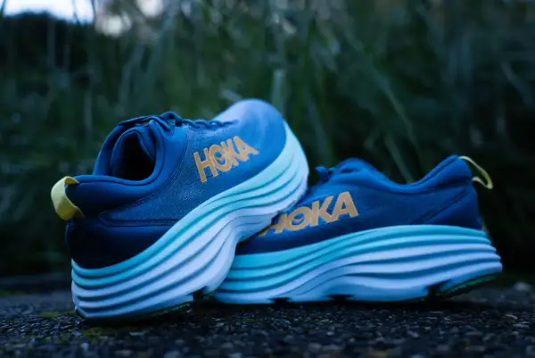Chaussures de course Hoka bleues avec semelles épaisses et ondulées, offrant le meilleur amorti pour vos foulées.