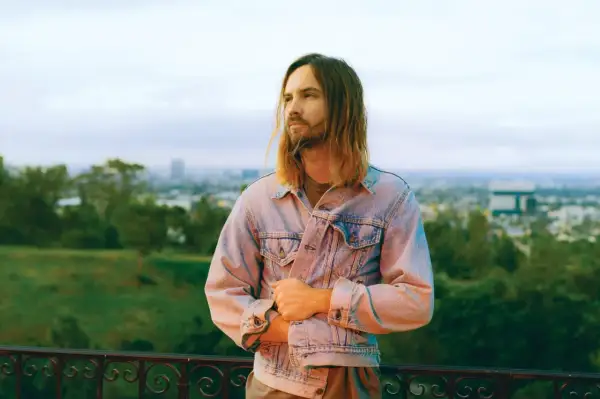 Kevin Parker z Tame Impala Polska w dżinsowej kurtce, z widokiem na miasto.