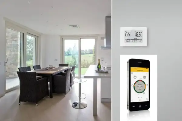 Termostato e cronotermostato: un confronto visivo. Un moderno soggiorno con tavolo da pranzo e un dispositivo di controllo della temperatura, accanto a uno smartphone che mostra un'app per la gestione della casa.