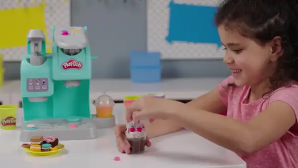 Dziewczynka bawi się w play doh kawiarnia, tworząc pyszne desery z plasteliny.
