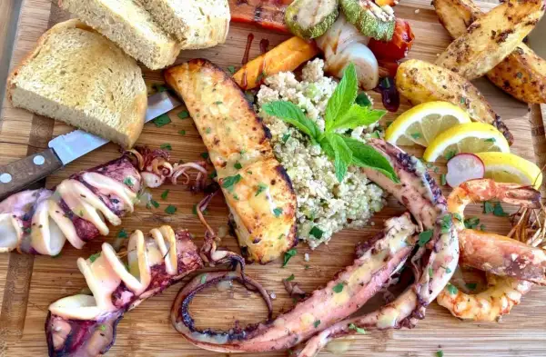 Wyśmienite greckie jedzenie: grillowane kalmary, krewetki, łosoś, pieczone ziemniaki, kasza i pieczywo.