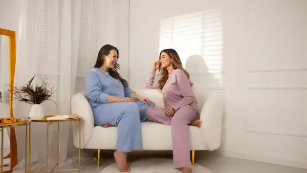 Dwie kobiety w pastelowych piżamach plus size rozmawiają na kanapie.