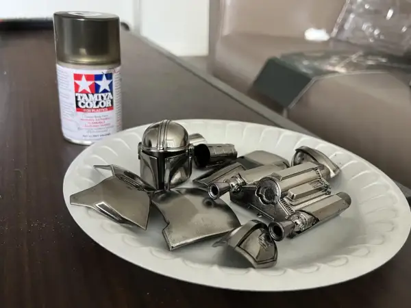 Vernice cromata spray Tamiya per plastica funziona. Pezzi di un elmo e armatura di un personaggio, come il Mandaloriano, pronti per essere assemblati.