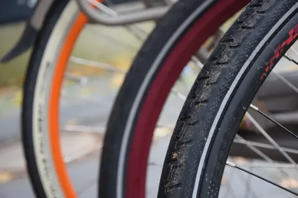 Zbliżenie na opony rowerowe 29 cali z widocznymi bieżnikami i obręczami w różnych kolorach.