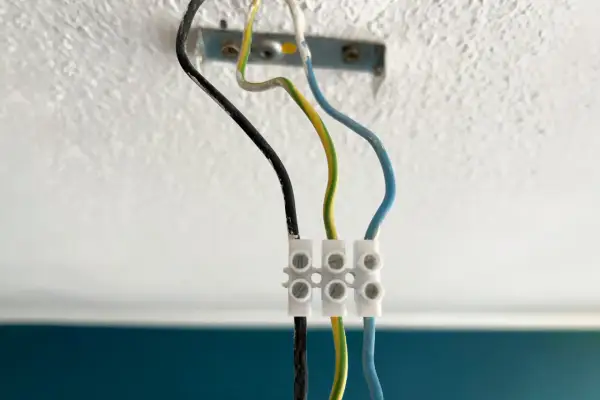 Drei Kabel (schwarz, grün-gelb, blau) sind mit einer Klemme verbunden, bereit zum Lampe abmontieren.