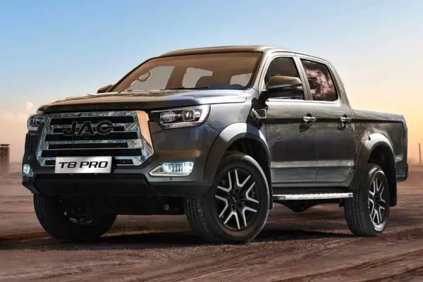 Ciemnoszary pickup JAC T8 PRO z chromowanym grillem i felgami stoi na piaszczystym podłożu.