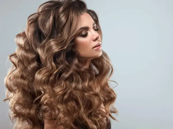 En kvinna med vackert, böljande brunt hår som ser ut att ha fått en fantastisk curly girl method-behandling.