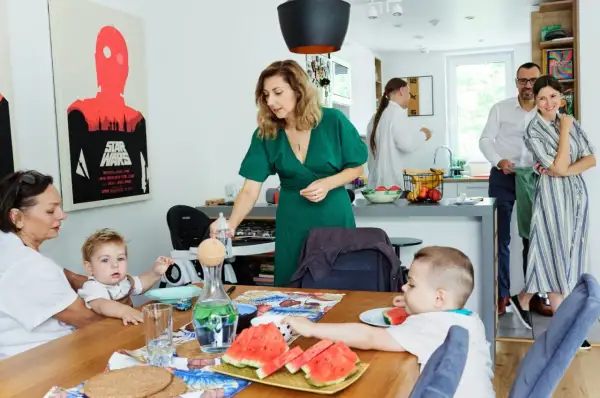 Rodzina przy stole, przygotowania do rodzinnego spotkania. Dzieci jedzą arbuzy, a dorośli rozmawiają. To piękne chrzest zdjęcia.