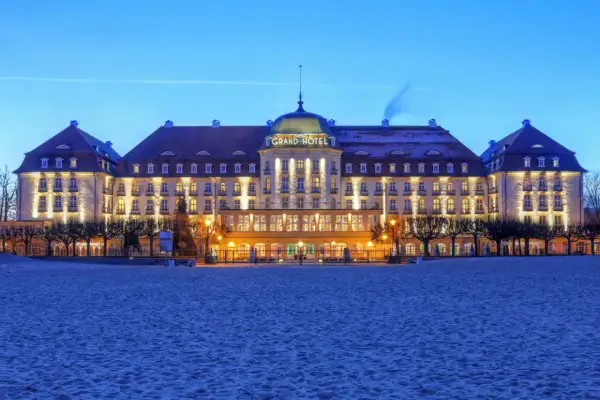 Grand Hotel w Sopocie, jeden z najpiękniejszych hoteli w Polsce, lśni nocą nad piaszczystą plażą.