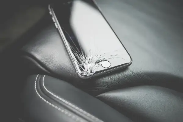 Uszkodzony ekran telefonu leżący na skórzanym siedzeniu.
