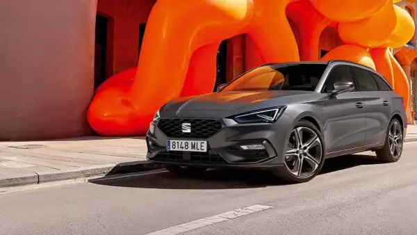 Grå Seat Leon Sportstourer parkerad framför en orange skulptur. En perfekt bil för en seat leon sportstourer test.