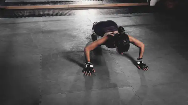 Femme en position de pompe, travaillant ses bras et son dos. Un exercice efficace pour tonifier le corps et réduire le bourrelet aisselle.