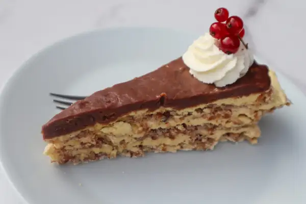 En bit chokladtårta med mandelbotten, grädde och vinbär. Ett perfekt recept på daimtårta med mandelbotten.