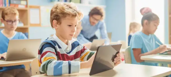 Kinder lernen mit Tablets und Laptops. Die Medien bedeutung in der Bildung ist heute enorm wichtig für die Zukunft.