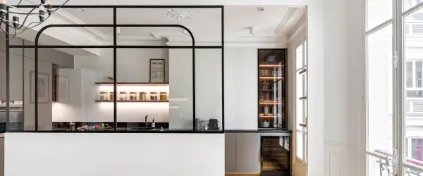 Elegante cocina semiabierta cristal con estantes iluminados, vitrina y vinoteca. Un espacio moderno y funcional.