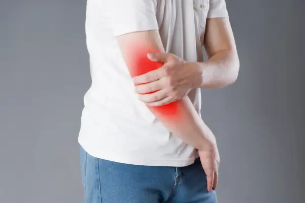 Person håller om sin arm där det lyser rött, vilket indikerar att det gör ont i underarmen.