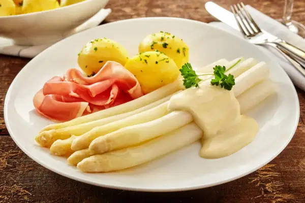 Spargel mit Sauce Hollandaise, Salzkartoffeln und Schinken. Die Menge der Sauce pro Person ist großzügig bemessen.