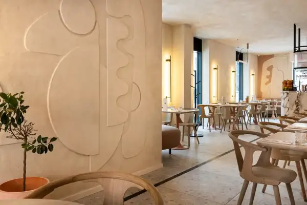 Nowoczesne wnętrze restauracji z dekoracyjnymi tynkami glinianymi na ścianach, geometrycznymi formami i minimalistycznymi meblami.