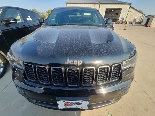 Czarny Jeep Limited, pokryty kurzem, z charakterystycznym grillem i logo Jeep.