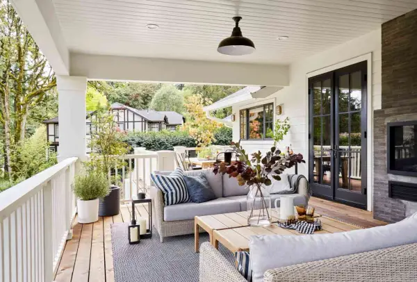 Cozy backyard makeover with a covered porch, outdoor sofa, coffee table, and fireplace.
