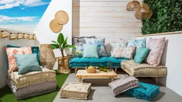 Acogedora zona chill out interior con cojines coloridos, suelo de césped artificial y luces de estilo bohemio.
