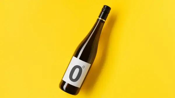 Bottiglia di vino dealcolato con etichetta "0" su sfondo giallo brillante.