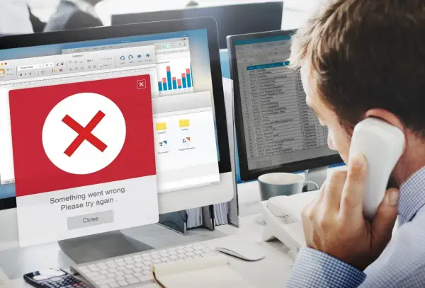 Błąd na ekranie komputera. Mężczyzna rozmawia przez telefon, próbując dowiedzieć się, jak usunąć się z administratora strony na FB.