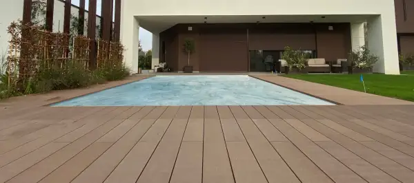 Ponte in legno effetto grana, ideale per esterni, circonda una piscina coperta. I requisiti dei pavimenti per esterni sono soddisfatti da questo materiale resistente e bello.