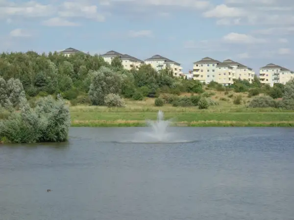 Widok na jezioro z fontanną i nowoczesne budynki mieszkalne na wzgórzu w Gdańsku Zakoniczyn.