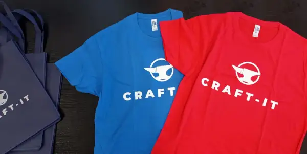 Niebieska i czerwona koszulka z logo "CRAFT-IT" i kowadłem. To przykład, jak sitodruk co to za technika, pozwala tworzyć trwałe nadruki na odzieży.