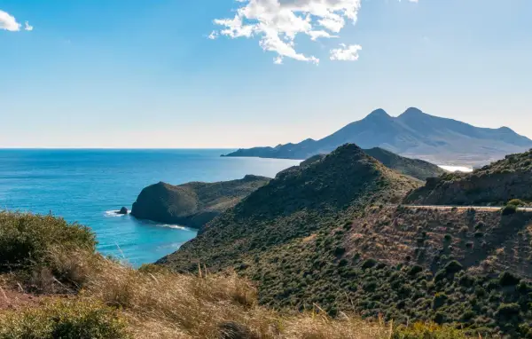 Paisaje costero en Cabo de Gata, con el mar azul intenso y montañas verdes.