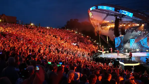 Tłumy rozbawionych ludzi na mrągowo festiwal, oświetlone sceną i kolorowymi światełkami.