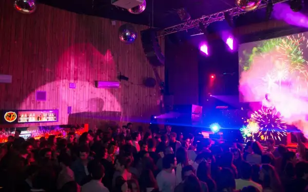 Festa al Macarena Club Barcelona, con luci stroboscopiche, DJ e fuochi d'artificio sullo schermo.