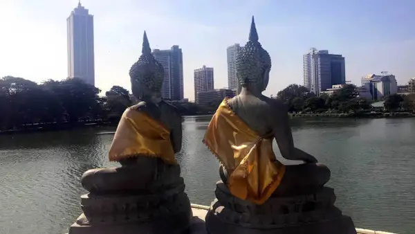 Dwie posągi Buddy z widokiem na nowoczesną panoramę stolicy Sri Lanki.
