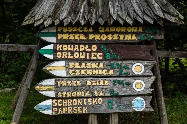 Drewniany drogowskaz leśny z nazwami szlaków, w tym "rudawiec najkrótszy szlak".