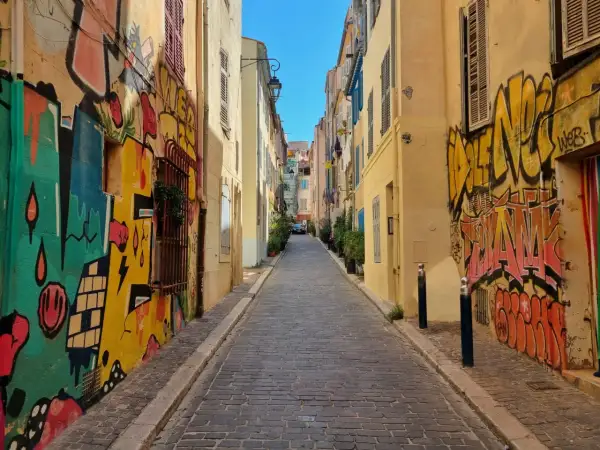 Kolorowa uliczka z brukowaną nawierzchnią, ozdobiona dynamicznym street art graffiti na ścianach budynków.