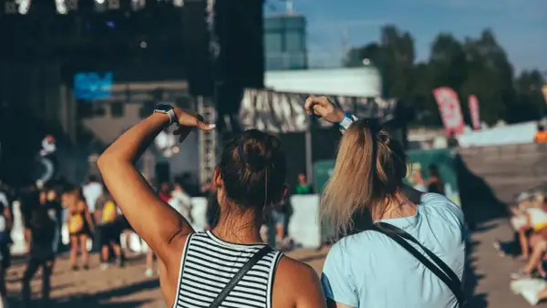 Dwie dziewczyny bawią się na koncercie podczas zielonego festiwalu, unosząc ręce w rytm muzyki.