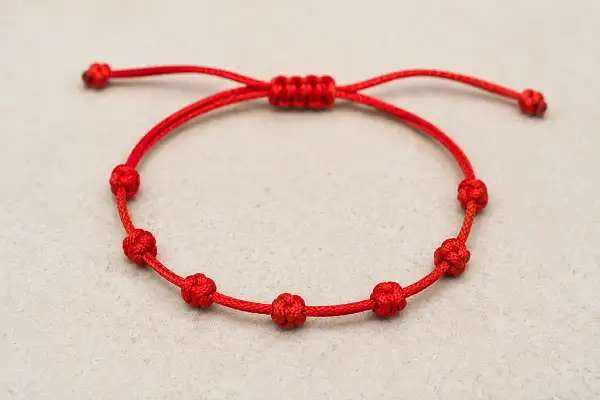 Pulsera roja con siete nudos, cada uno con su propia historia y significado.