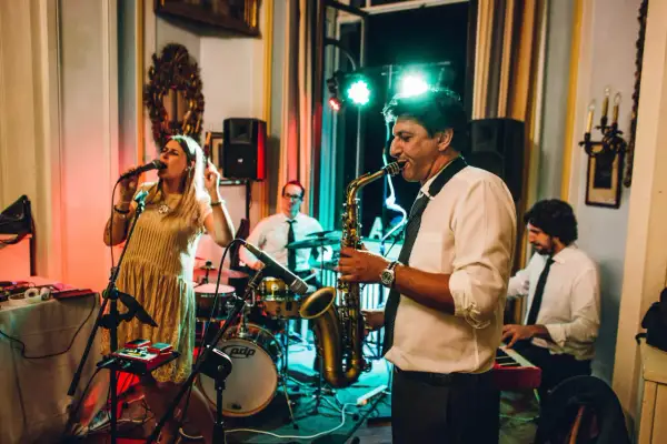 Una band suona musica dal vivo per un matrimonio. La cantante è in primo piano, mentre un sassofonista, un batterista e un tastierista completano il gruppo.