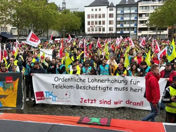 Große Menschenmenge bei einem Telekom-Streik. Sie fordern "Ordentliche Lohnerhöhung für Telekom-Beschäftigte muss her!". Viele Fahnen und gelbe Westen sind zu sehen.