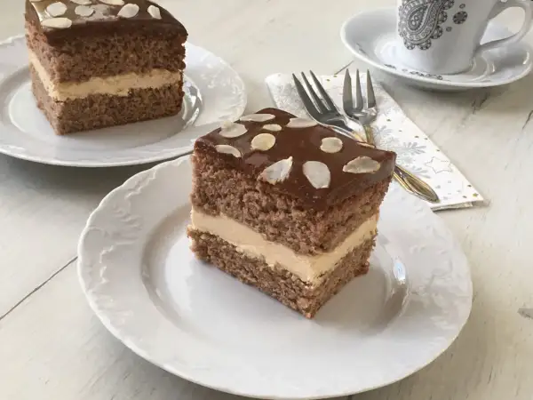 Pyszne ciasto z mascarpone i kajmakiem, polane czekoladą i posypane płatkami migdałów. Idealne na deser.