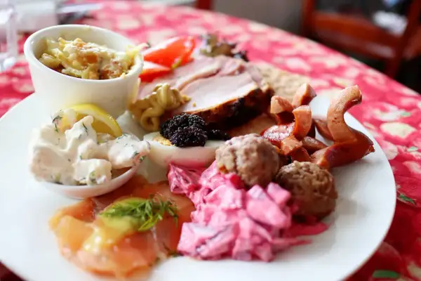 En härlig tallrik med godsaker på julbordet: lax, köttbullar, sill, ägg, rödbetor, korv och en liten skål med gratäng.