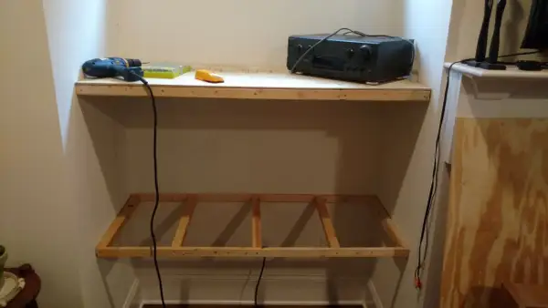 DIY project: a drill, level, and audio receiver sit on a wooden shelf, with a frame for another shelf below, showing how to hang shelves.